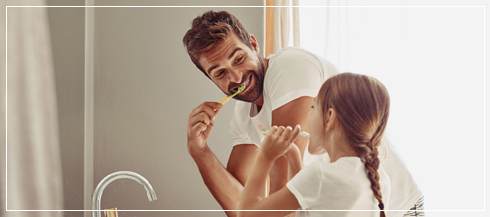 father and daughter brushing their teeth together